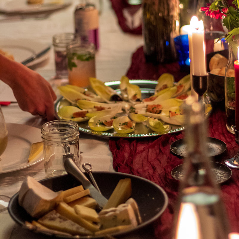 Dining table set with plates, cutlery, and candles in a warm, cozy setting.